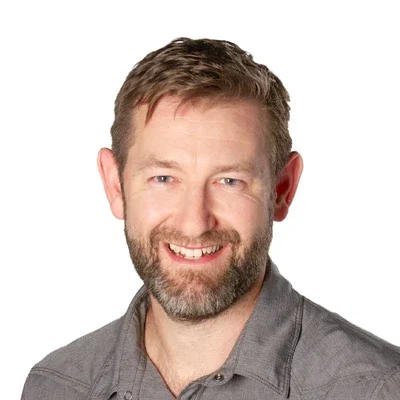 Chris McDonald smiling in a grey shirt.