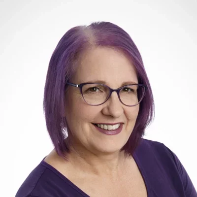 Kim smiling in a purple shirt.